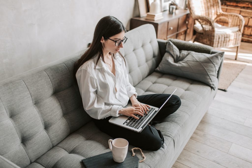 Woman sitting on a couch, tracking her shipment using a laptop