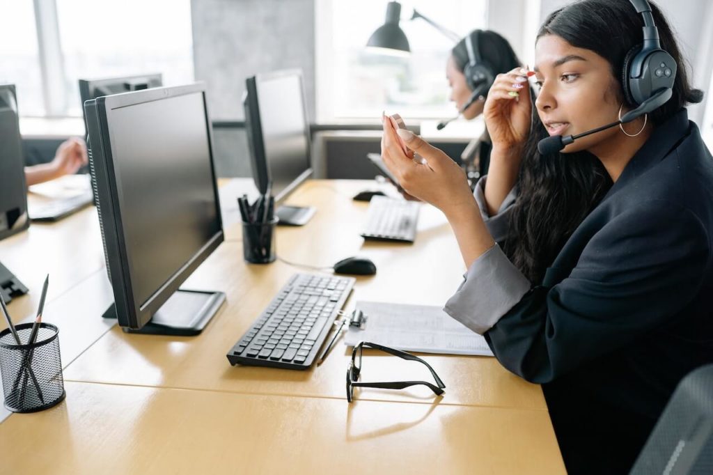 Woman working in the office with a headset on while talking to a customer over the phone