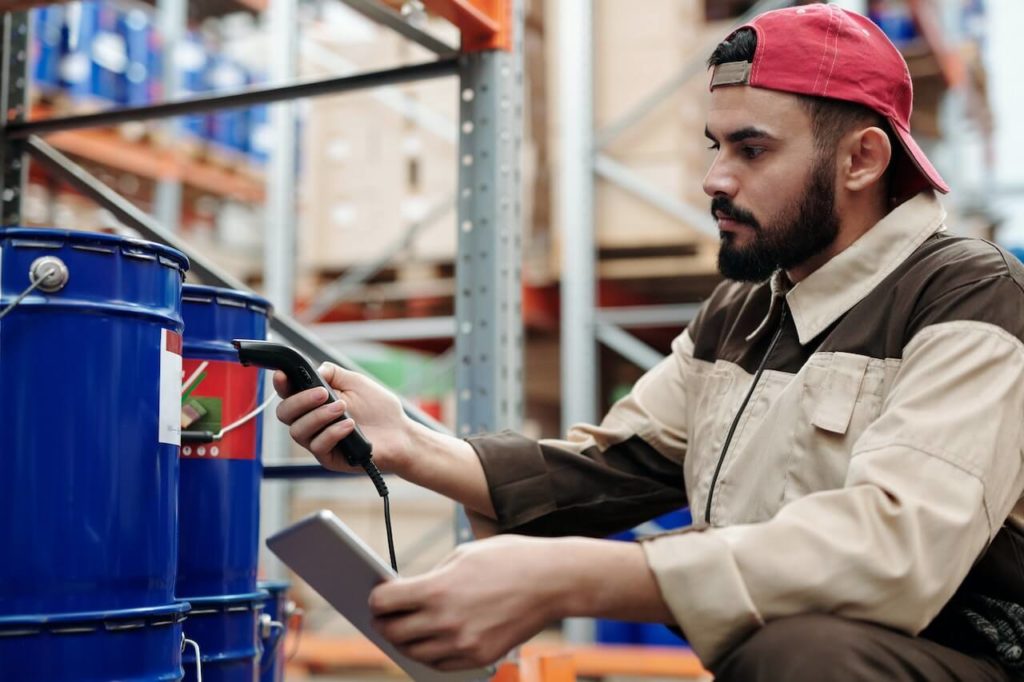 Man scanning the barcode of a container with a tablet in his hand