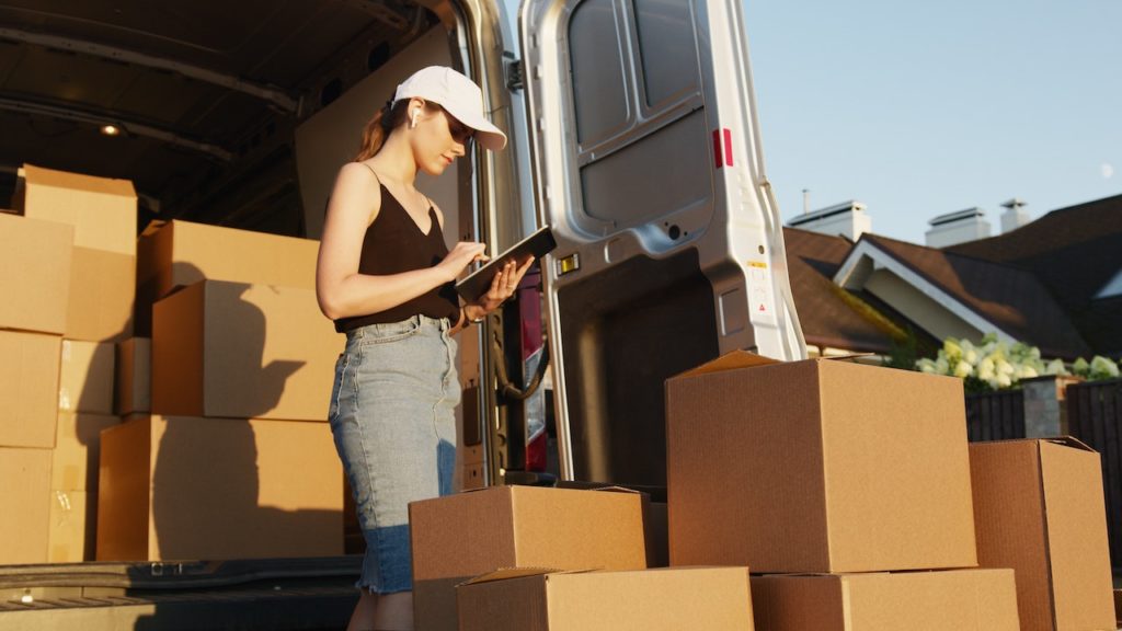 Woman standing outside a delivery van with cardboard boxes around her.