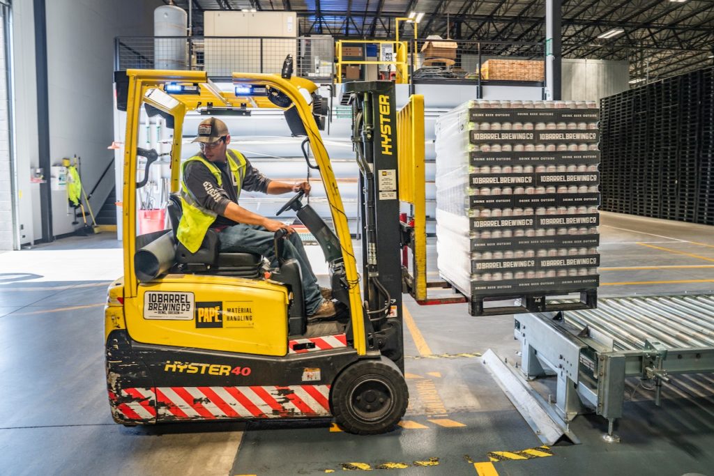 Man driving a forklift inside a warehouse.