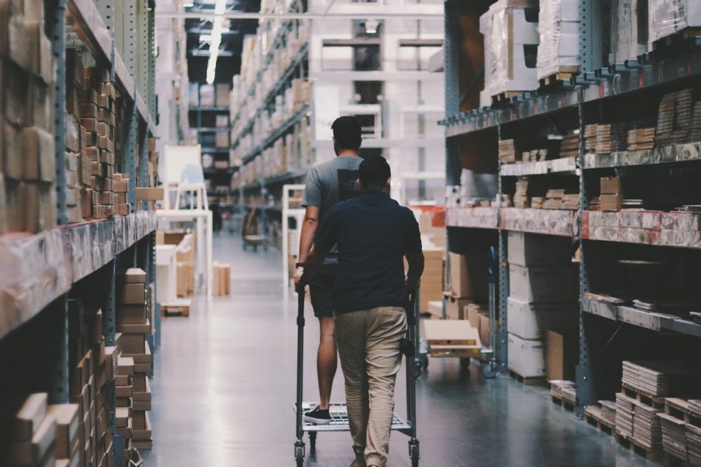 Two people walking down a warehouse aisle