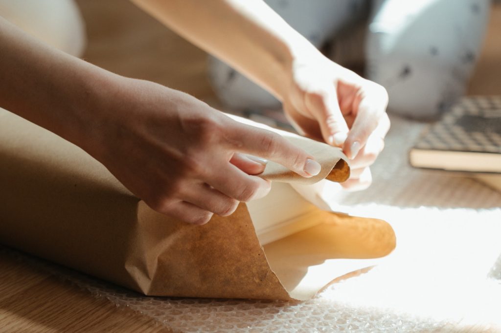 A person wrapping a book with brown paper